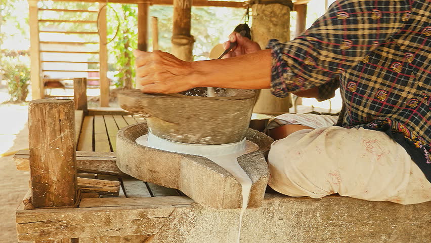 Woman Turning A Millstone To Grind Wet Rice For Making Liquid Rice