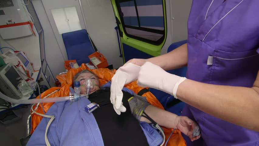 Paramedic Provide Emergency Medical Care To Critical Patient In Ambulance Preparing An Iv Drip