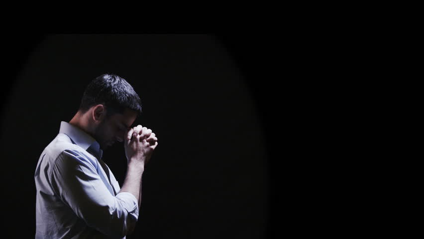 Attractive Young Man Putting His Hands Together In Prayer Against A