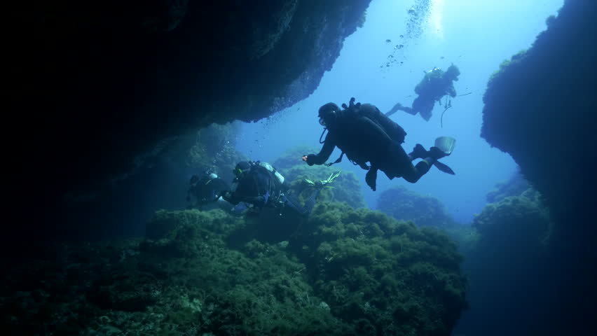 Underwater Shot Of Scuba Divers Entering A Huge Underwater Cave In ...