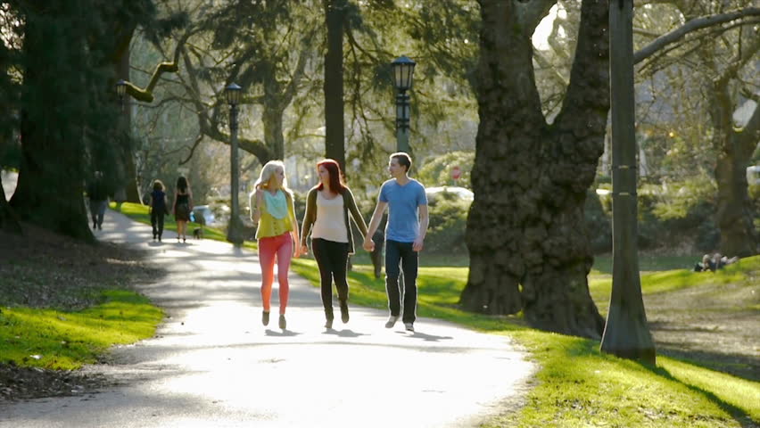 3 Happy Friends Walk Down Path Through Park Toward Camera Stock Footage ...